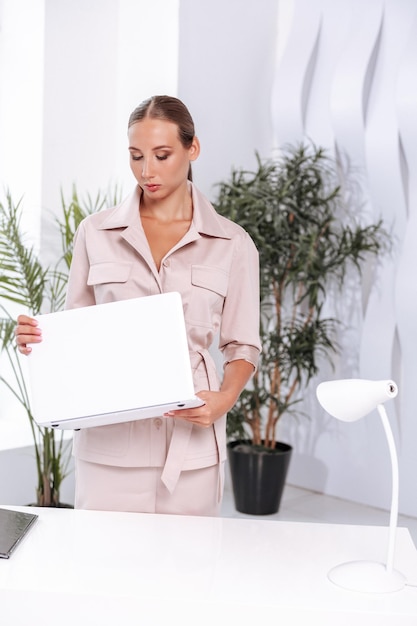 Een aantrekkelijke vrouw werkt op kantoor zit aan tafel werkt op een computer houdt een map vast