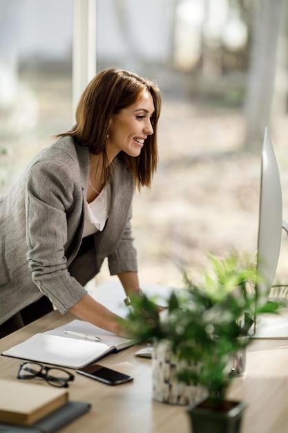 Een aantrekkelijke zakenvrouw die op de computer in haar thuiskantoor werkt.