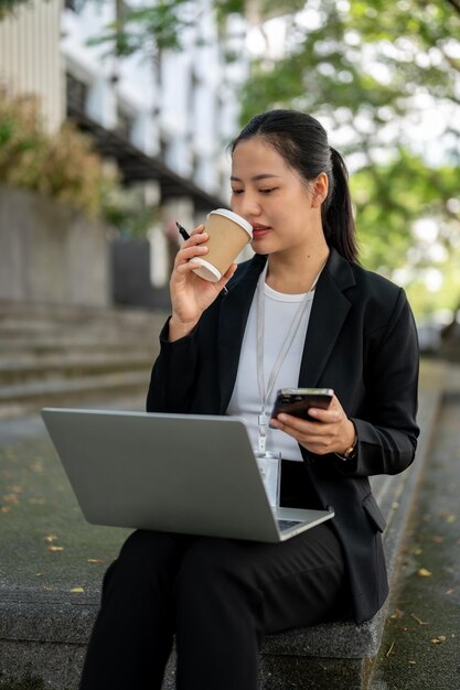 Een aantrekkelijke zakenvrouw drinkt haar ochtendkoffie terwijl ze op haar laptop op de trap werkt