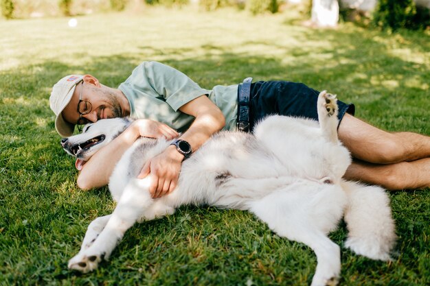 Een aardige man die met een hond op het gras ligt