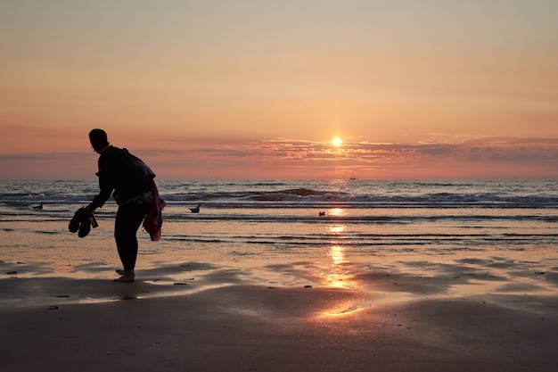 Een achteraanzicht van een dame op het strand die geniet van de schilderachtige zonsondergang