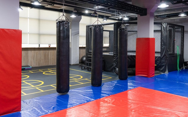 Een achthoekige kickbokskooi met bokszakken in het sportcomplex