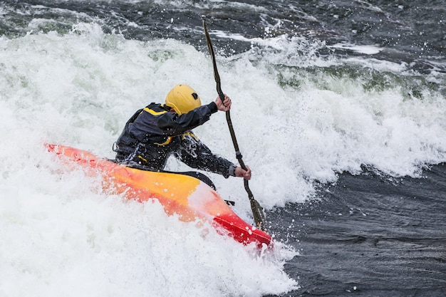 Een actieve mannelijke kajakker die rolt en surft in ruw water