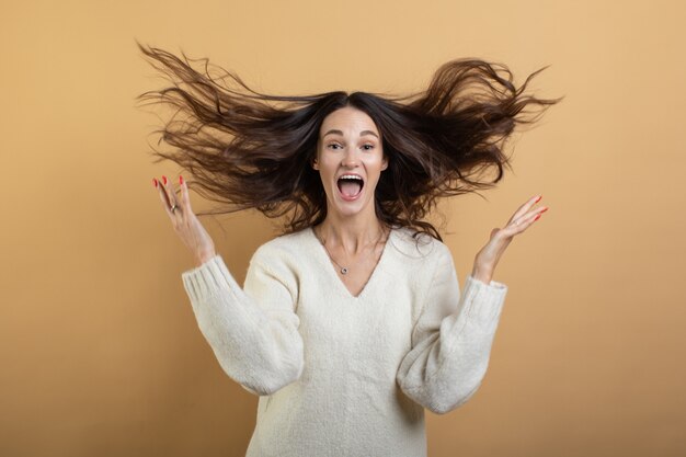 Een afbeelding van een jonge mooie vrouw in een witte trui die zich voordeed op een geïsoleerde oranje achtergrond