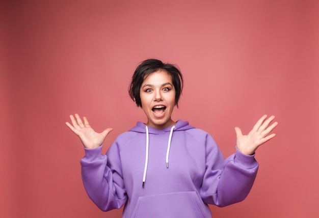 Een afbeelding van een opgewonden schreeuwende jonge vrouw geïsoleerd op een roze achtergrond Een weergave camera studio portret