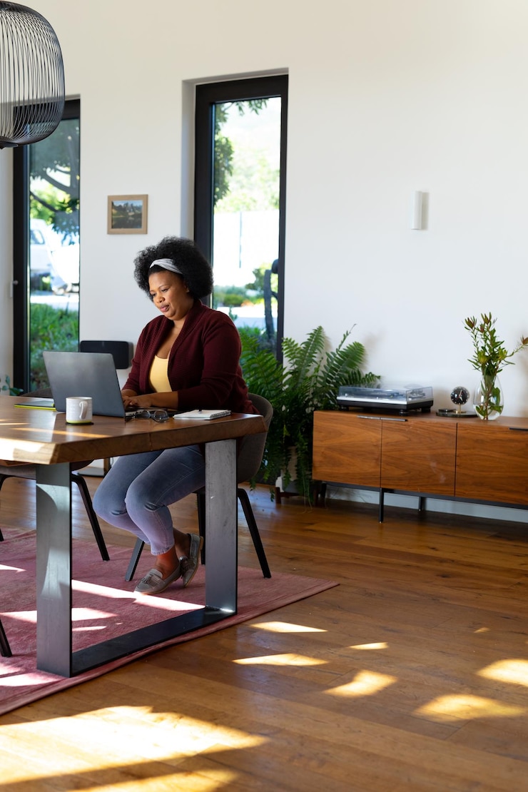 Foto een afrikaans-amerikaanse vrouw zit aan tafel, concentreert zich en gebruikt een laptop.