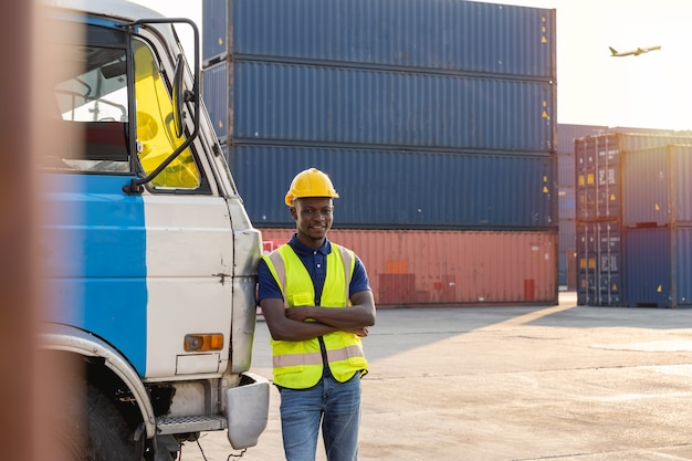 Een afrikaanse vrachtwagenchauffeur stond te rusten en vrolijk te glimlachen naast de vrachtwagen. in het containermagazijn