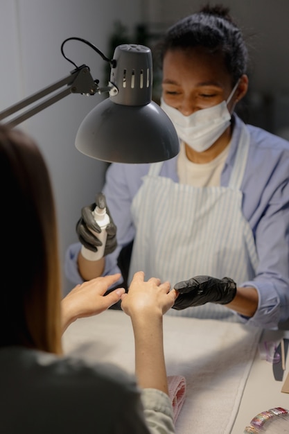 Een afrikaanse vrouw doet een manicure voor een europese vrouw het proces van manicure in een studio of schoonheid