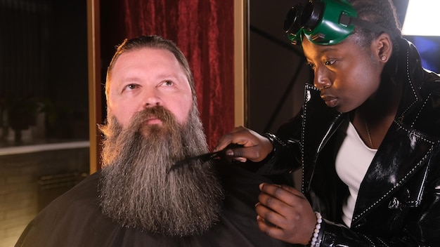 Een Afro-Amerikaans kappersmeisje kamt en knipt de baard van een man
