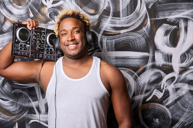 Een Afro-Amerikaanse DJ met een DJ-console in een club tegen een muur met graffiti