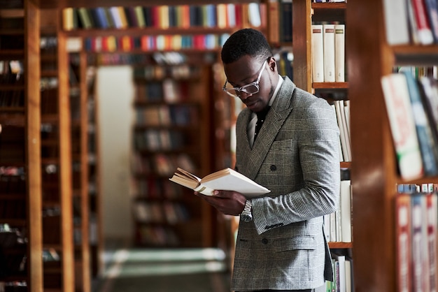 Een Afro-Amerikaanse man in een pak staande in een bibliotheek in de leeszaal.