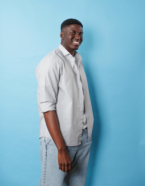 Een Afro-Amerikaanse man in witte kleren staat op een afgelegen blauwe achtergrond