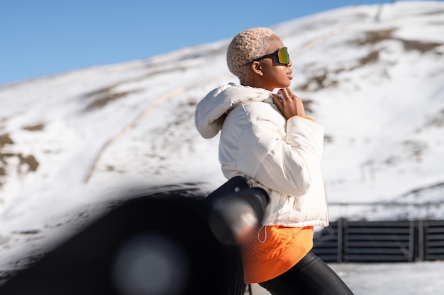 Een Afro-Amerikaanse vrouw die in de winter een sneeuwbril draagt op een besneeuwde berg