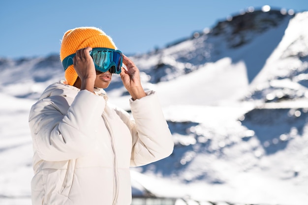 Een Afro-Amerikaanse vrouw die in de winter een sneeuwbril draagt op een besneeuwde berg