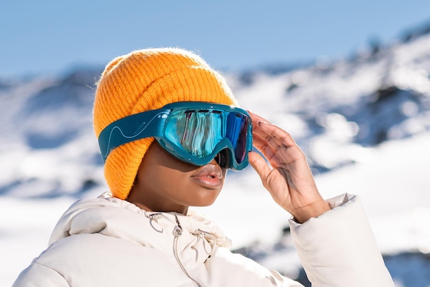 Foto een afro-amerikaanse vrouw die in de winter een sneeuwbril draagt op een besneeuwde berg