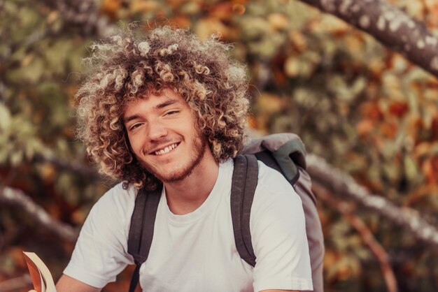 Een afro-tiener ontspant tijdens het lezen van een boek zittend in het bos bij mooi herfstweer. Foto van hoge kwaliteit