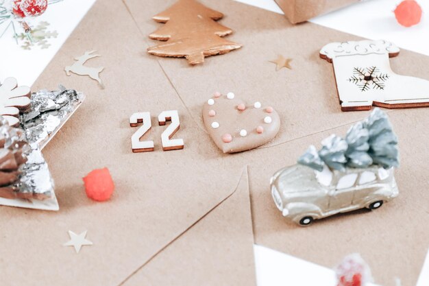 Een ambachtelijke envelop met houten nummer 22 koekjes kerstdecor en een vuren tak op een witte achtergrond