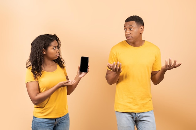 Een ander leven online Boze Afro-Amerikaanse dame die de mobiele telefoon van haar man controleert en de man om uitleg vraagt