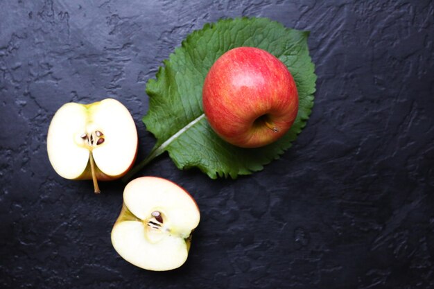 Een appel met groene bladeren die zwarte achtergrond liggen. Stilleven foto. Gezonde stijl. Fruit en natuur.