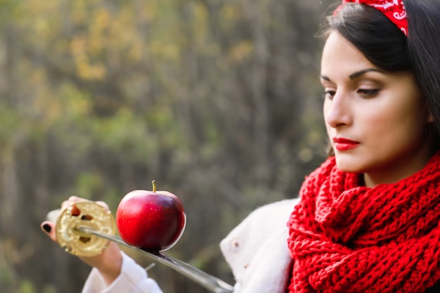 Een appel op de rand van een zwaard in de handen van een jonge vrouw. Japans zwaard.