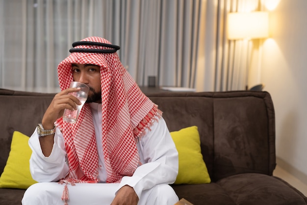 Een arabische jongeman die water drinkt met een glas