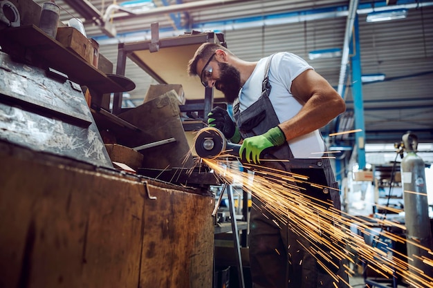 Foto een arbeider in de zware industrie die metalen onderdelen snijdt met een metaalsnijder metaalbewerker slijpen in de werkplaats