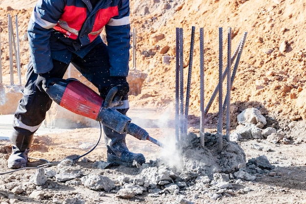 Een arbeider met een drilboor breekt betonnen palen De paalkop vellen met een handgereedschap Voorbereiding van palen voor het monteren van de fundering