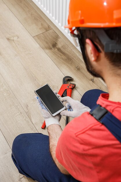 Een arbeider met een oranje helm installeert radiatoren in huis