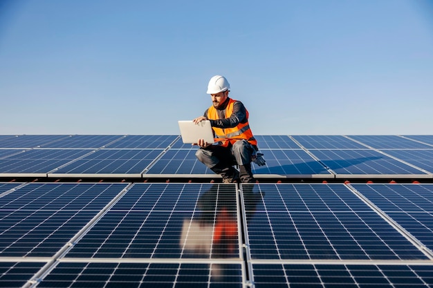 Een arbeider op het dak met behulp van een laptop die is opgeladen door zonne-energie