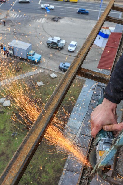 Een arbeider snijdt metaal met een slijper