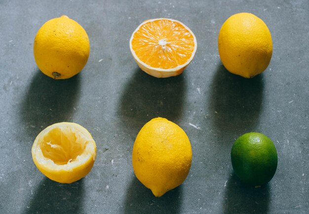 Een arrangement van citrusvruchten, citroenen, sinaasappel en limoenen op een grijze achtergrond.