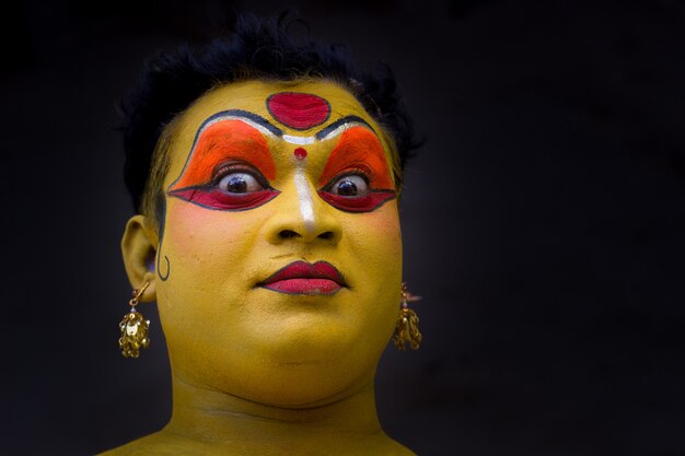 Een artiest doet make-up op het gezicht voor een optreden op het podium tijdens een Indiaas festival