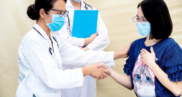 Een arts en een patiënt met een masker schudden elkaar de hand na het voltooien van de behandeling.