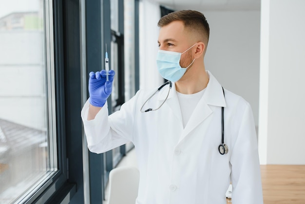 Een arts in blauwe handschoenen die een fles met vaccin vasthoudt Close-up shot Geneeskunde en gezondheidszorg concept