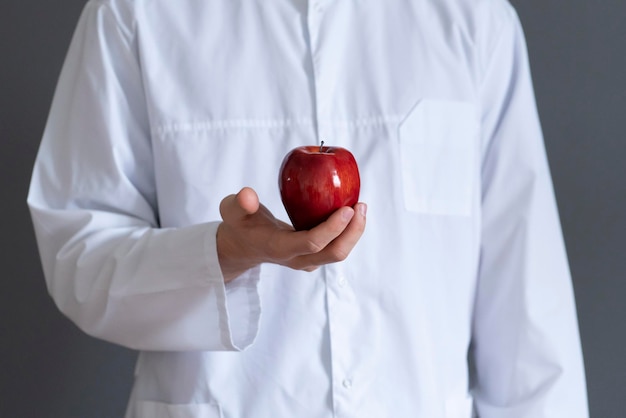 Een arts in wit uniform die een rauw fruit geeft aan de patiënt die een gezond voedingsconcept eet