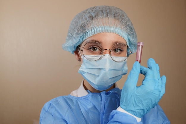 Een arts met een beschermend masker en een bril houdt een reageerbuis vast met een positieve bloedtest voor COVID19