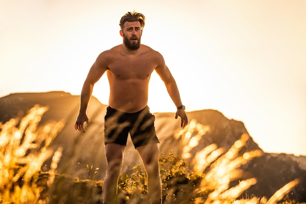 Een atleet die in de vroege ochtend conditietraining doet bovenop een berg met de zonsopgang op de achtergrond.