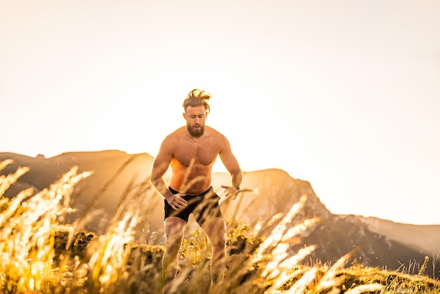 Een atleet die in de vroege ochtend conditietraining doet bovenop een berg met de zonsopgang op de achtergrond.