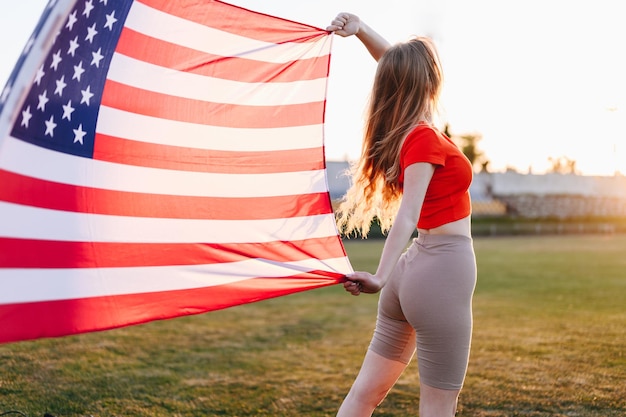Een atleet met Amerikaanse vlag met een Amerikaanse vlag op zonsondergang ontwikkelt zich op Wind Woman in rode top