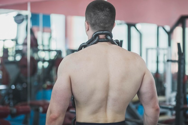 een atleet staat in een sportschool met een grote ketting om zijn nek