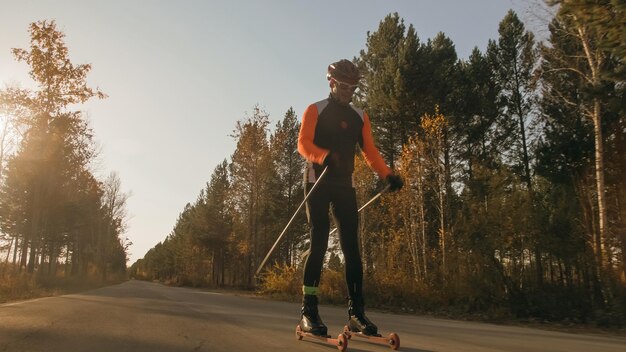 Een atleet trainen op de rolschaatsers Biatlonrit op de rolski's met skistokken in de helm Herfsttraining Rolsport