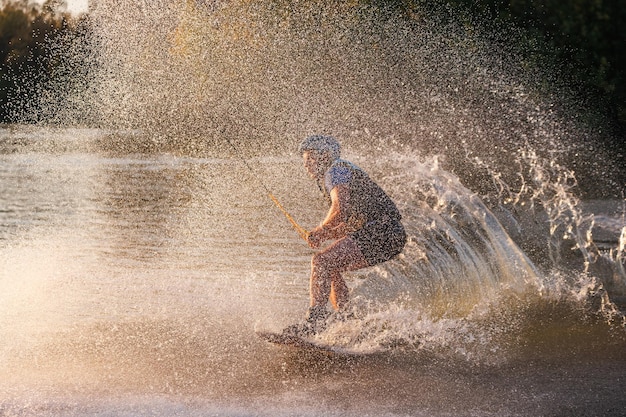 Een atleet voert een truc uit op het waterpark bij zonsondergang Wakeboard-rijder