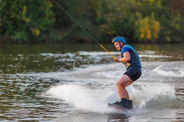 Een atleet voert een truc uit op het waterpark bij zonsondergang Wakeboard-rijder