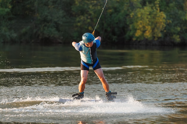 Een atleet voert een truc uit op het waterpark bij zonsondergang Wakeboard-rijder