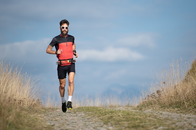 Een atletenagent met een baard leidt op een bergweg op