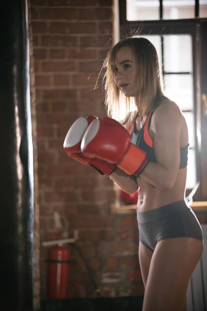 Een atletische vrouw in bokshandschoenen die in de sportschool staat