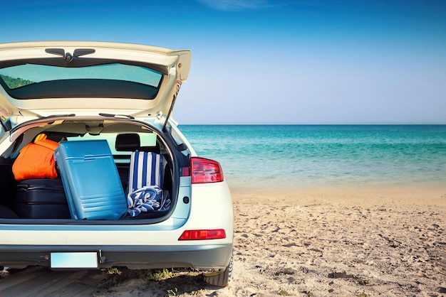 Een auto met open kofferbak op een strand