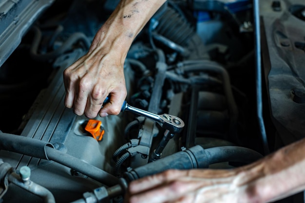 Een automonteur werkt met een automotor in de garage van de monteur. Autoreparatieclose-up