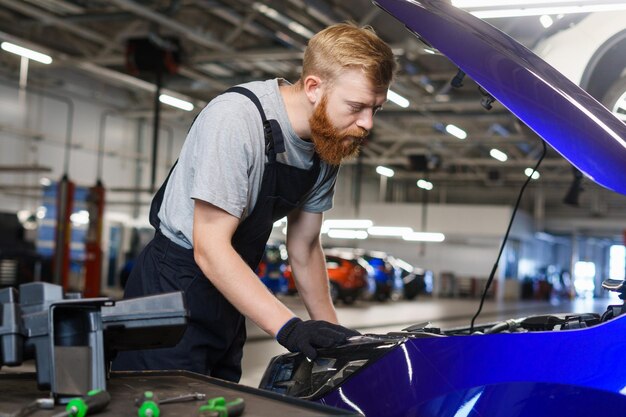 Een autoservicemedewerker tijdens het werk aan het vervangen van filters en olie in de automotor Professioneel tankstation