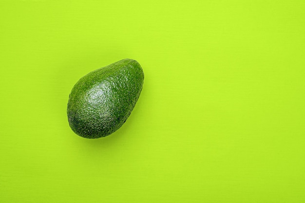 Een avocado op groene achtergrond, bovenaanzicht.